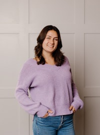 a woman wearing a lilac sweater and jeans